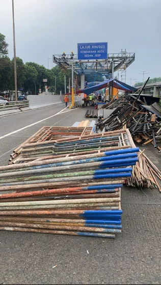 Tumpukan pipa scaffolding bercat biru dan oranye di area terbuka