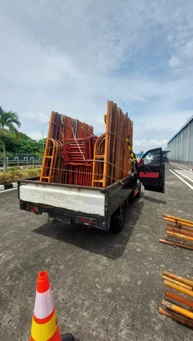 Kendaraan pick-up berisi frame scaffolding di tepi jalan area pergudangan