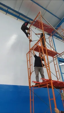 Pekerja memanjat menara scaffolding di dalam ruangan